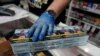 An employee of a tobacco shop sells a pack of cigarettes at the Vallecas neighborhood, in Madrid, Spain March 13, 2020.