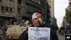A wounded demonstrator carries a poster in Cairo, Egypt, Monday Jan. 31, 2011