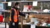 FILE - In this photo released by Xinhua News Agency, a staff member disinfects parcels at a community where a locally transmitted COVID-19 case was found, in Haidian district, Beijing, China, Jan. 18, 2022.