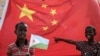 FILE - A boy holds the Djiboutian national flag in front of the Chinese national flag before the launching ceremony of China-financed 1,000-unit housing construction project in Djibouti, July 4, 2018. 