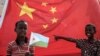 FILE - A boy holds the Djiboutian national flag in front of the Chinese national flag as he waits for Djibouti’s president, Ismaïl Omar Guelleh, before the launching ceremony of a China-financed 1,000-unit housing construction project in Djibouti, July 4, 2018.