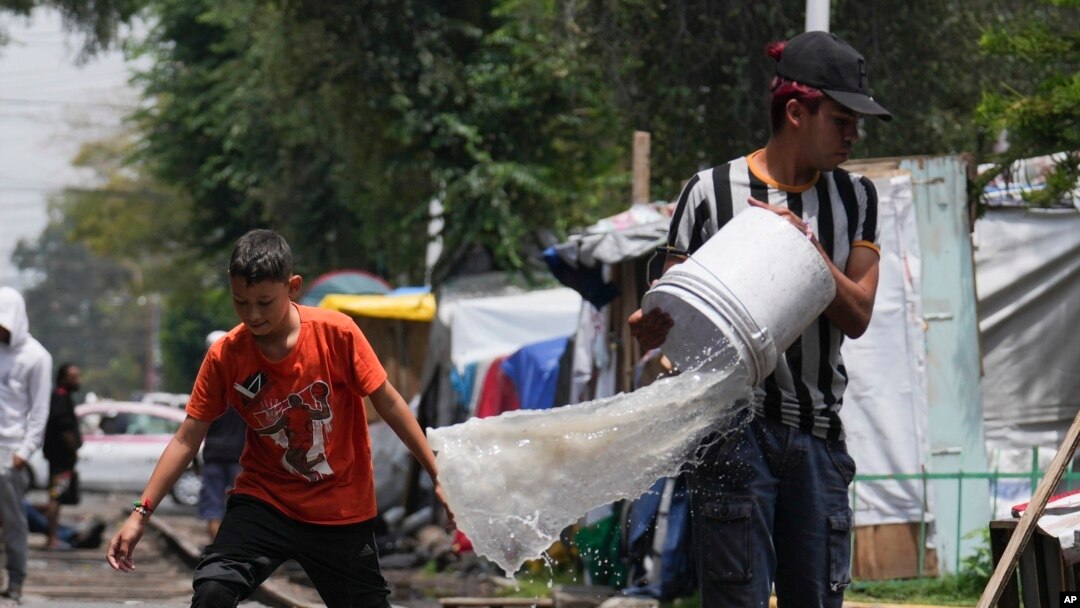 ARCHIVO - La gente drena el agua de sus tiendas de campaña después de las fuertes lluvias en un campamento de migrantes en las vías del tren de Vallejo en la Ciudad de México, el jueves 18 de julio de 2024.