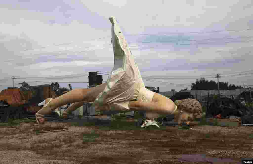 A giant statue of U.S. actress Marilyn Monroe is seen at the dump site of a garbage-collecting company in Guigang, Guangxi Zhuang Autonomous Region, China, June 18, 2014. The eight-meter-tall stainless steel statue, which weighs about eight tons, was made by several Chinese artists for over two years, based on the famous scene from her movie "The Seven Year Itch".