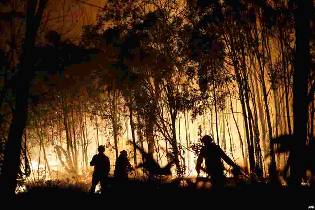Firefighters battle a blaze on Fingerfield road at the Deepwater National Park area of Queensland, Australia.