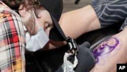 FILE - A tattoo artist works at a shop in Cleveland, May 15, 2020.