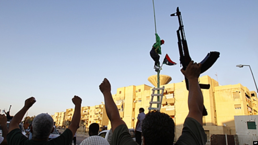Libyan rebels gesture as they change the flag in Abu Salim district in Tripoli, Libya, August 25, 2011