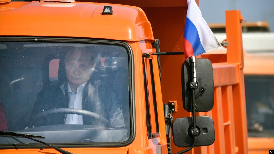 Russian President Vladimir Putin drives a truck to officially open the much-anticipated bridge linking Russia and the Crimean peninsula, during the opening ceremony near in Kerch, Crimea, Tuesday, May 15, 2018. (Alexander Nemenov/Pool Photo via AP)