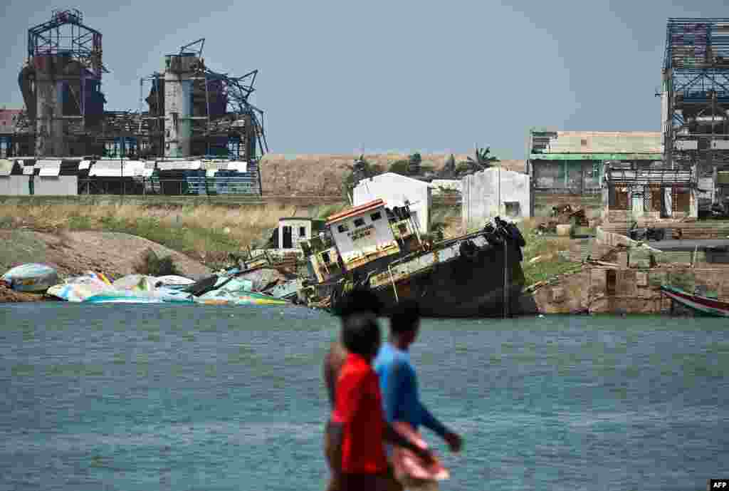 Indian fishermen look at boats destroyed by cyclone Phailin at the Gopalpur Port.
