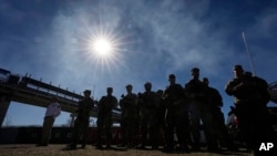 Integrantes de la Guardia Nacional de pie mientras el gobernador de Texas, Greg Abbott, y otros gobernadores, ofrecen una conferencia de prensa para discutir la Operación Estrella Solitaria y temas fronterizos, el domingo 4 de febrero de 2024, en Eagle Pass, Texas.