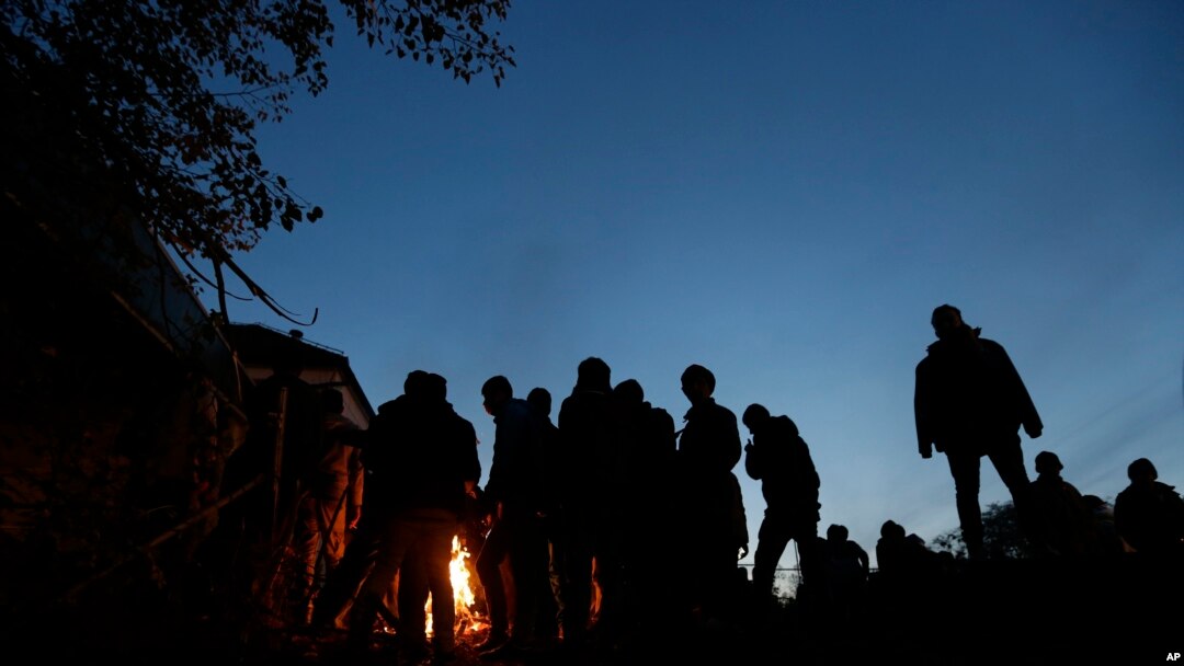 Migrants warm up by fire while waiting to enter a camp in Spielfeld, Austria, Sunday, Oct. 25, 2015.