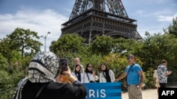 Tourists pose in front of the Eiffel Tower in the background in Paris on Aug. 4, 2024, during the Paris 2024 Olympics games. 