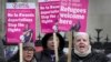 FILE - Campaigners hold signs outside the High Court in London, Dec. 19, 2022, protesting United Kingdom's controversial plan to deport some asylum-seekers to Rwanda. A UK official arrived in Rwanda on Saturday to reinforce the UK government's commitment to the plan.
