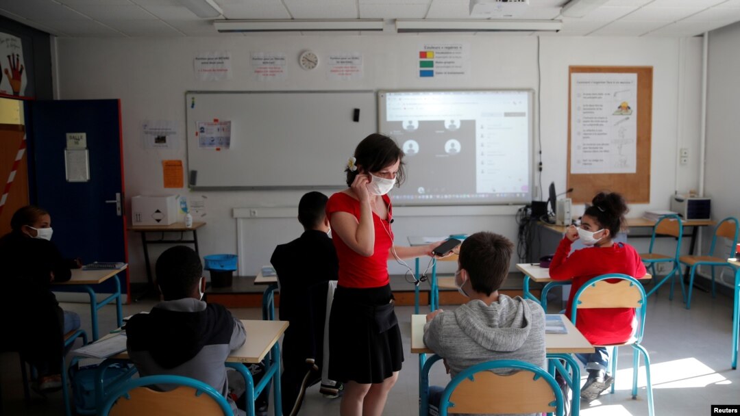 Una maestra y alumnos en Francia usan máscara, en una mezcla de clases en línea y presenciales en Nantes, al reabrir el país en mayo de 2020.