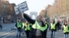 A man wearing a yellow vest, a symbol of French drivers' protest against higher fuel prices, holds a placard with the message, "World Champions in Taxes," as demonstrators gather on the Champs Elysees in Paris, France, Nov. 17, 2018. 
