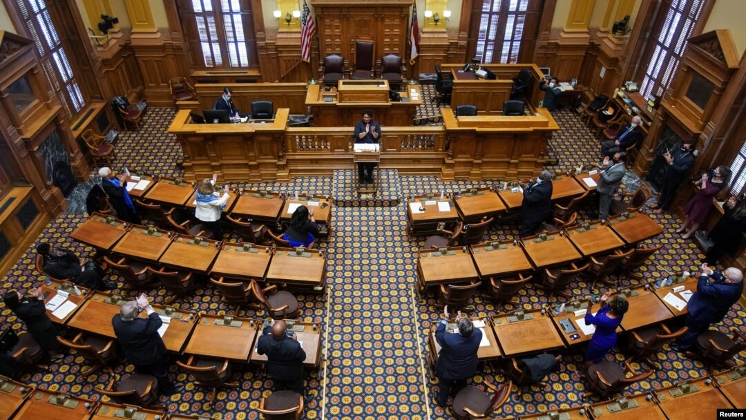 Los electores del Colegio Electoral Demócrata, encabezados por la electora Stacey Abrams, se ponen de pie y aplauden después de votar por el presidente electo Joe Biden en el Senado del Estado de Georgia el 14 de diciembre de 2020.