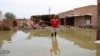 FILE - A man gestures as he wades through a flooded road in the town of Salmaniya, about 35 km southwest of the capital, Khartoum, Sudan, Sept. 17, 2020.