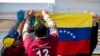 Migrantes venezolanos cuelgan una bandera nacional venezolana durante la consulta popular convocada por la oposición venezolana. Bogotá, Colombia. Diciembre 12, 2020.
