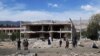 FILE - Afghan security personnel inspect the site of a car bomb blast near the destroyed office building of Afghanistan's intelligence agency in the city of Aybak on July 13, 2020. 