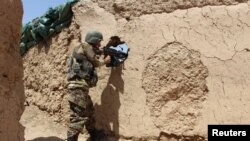 阿富汗国民军士兵在阿富汗赫尔曼德省巴巴吉一处哨所阵地严阵以待。