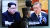 A South Korean marine passes by a TV screen showing file footage of South Korean President Moon Jae-in and North Korean leader Kim Jong Un, during a news program at the Seoul Railway Station in Seoul, South Korea, April 18, 2018.