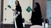 FILE - Saudi women hold national flags as they walk on a street during Saudi National Day in Riyadh, Saudi Arabia.