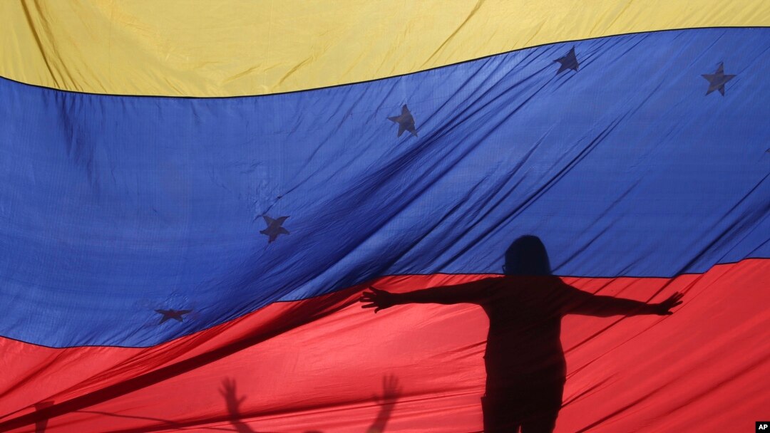 Foto de archivo de las siluetas de manifestantes antigubernamentales a través de una bandera venezolana durante una protesta en Caracas, Venezuela. Julio 10, 2017