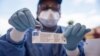 A nurse working with the World Health Organization (WHO) shows a bottle containing Ebola vaccine at the town all of Mbandaka on May 21, 2018, during the launch of the Ebola vaccination campaign.