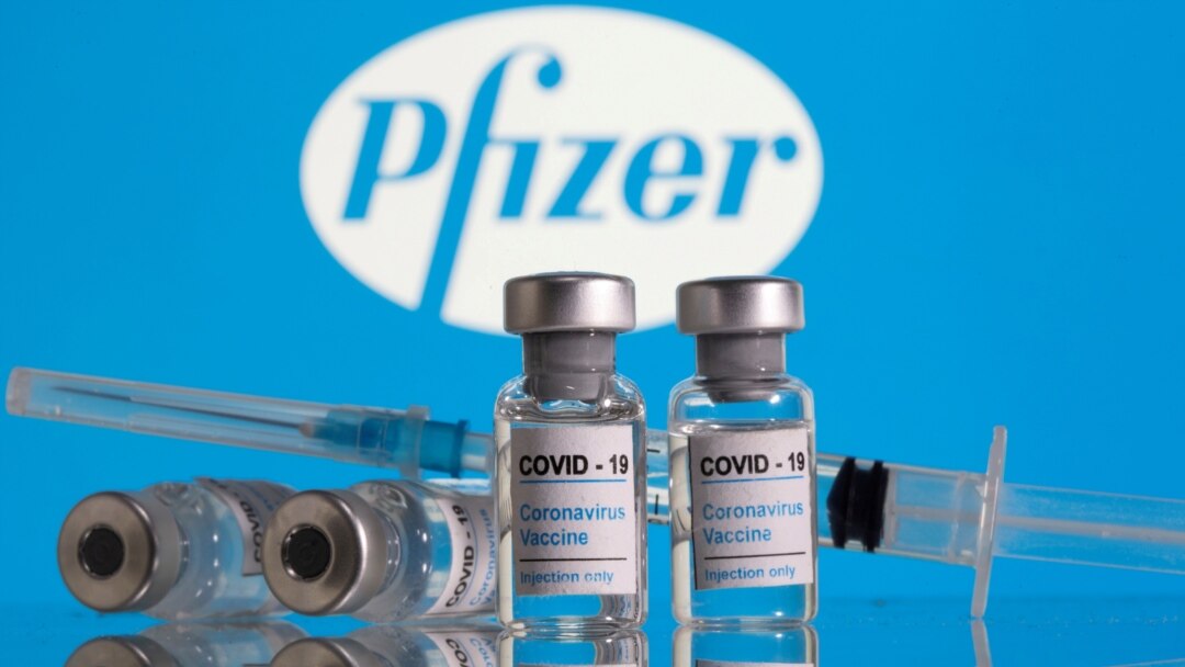 FILE - Vials labelled 'COVID-19 Coronavirus Vaccine' and a syringe are seen in front of the Pfizer logo in this illustration taken Feb. 9, 2021.