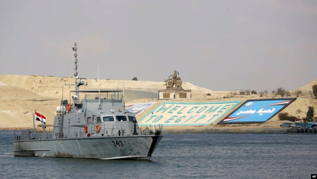 FILE - A cargo ship sails through the town of Ismailia, Egypt, March 30, 2021, as traffic resumed through the Suez Canal after it was blocked by a massive ship that had been stuck sideways for nearly a week.