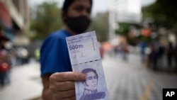 Una mujer muestra un nuevo billete de 500.000 bolívares después de retirarlo de un banco en Caracas, Venezuela, el martes 16 de marzo de 2021.