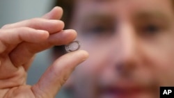 FILE - In this Jan. 15, 2014 file photo, Brian Otis, Google X project lead, holds a contact lens Google is testing to explore tear glucose in Mountain View, Calif.
