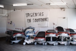 FILE - A banner reading "Emergency services are suffering" above empty stretchers in the hall of the emergency services of the Aix Hospital Center in Aix-en-Provence, southern France, April 3, 2020.