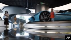A child pose for photos near a race car displayed at the NIO flagship store in Beijing on Thursday, Aug. 20, 2020. The chairman of Chinese electric car brand NIO says it plans to start expanding to Western markets next year. William Li said the…