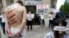 FILE - Reporters Without Borders activists, bound and made up as mock victims, demonstrate outside the Iran Air office on the Champs Elysées in Paris, July 10, 2012, to protest the imprisonment of Iranian journalists.