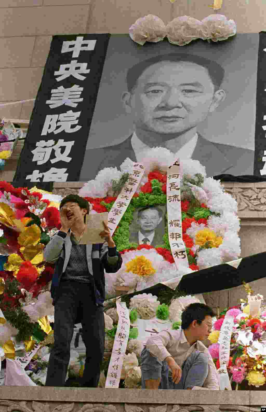 中国学生在北京天安门广场上的人民英雄纪念碑前展示胡耀邦像和“民主之光耀邦”等标语(1989年4月19日) 。1989年4月15日,抑郁中的胡耀邦突然心梗病逝,引发民众不满和自发悼念,学生游行,抬着写有“民族魂”大字的旗子。 1989年4月22日,成千上万的示威者高呼“民主万岁”,涌入北京市中心的天安门广场,为胡耀邦送葬。