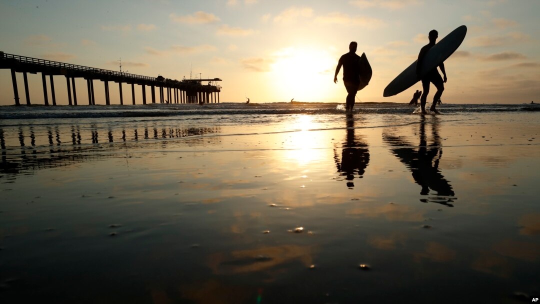 Surfers leave the water next to Scripps Pier, Aug. 2, 2018, in San Diego. A recent measurement of seawater temperature off Scripps Pier broke a record — it reached 79.5 degrees Fahrenheit on Aug. 9.