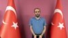 Selahattin Gulen, a nephew of U.S.-based Muslim cleric Fethullah Gulen, stands between Turkish flags in this photo provided by Turkish intelligence service, May 31, 2021, in Ankara, Turkey.