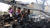 FILE - Yemeni men inspect the damage at a factory allegedly targeted by Saudi-led coalition's airstrikes in the Red Sea town of Hodeida, July 27, 2018.