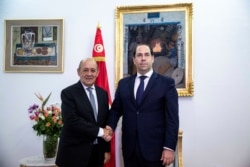 Tunisian Prime minister Youssef Chahed, right, shakes hands with French Foreign Minister Jean-Yves Le Drian, in Tunis, Jan. 9, 2020.