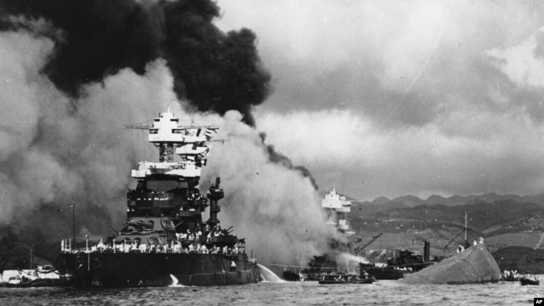 FILE - In this Dec. 7, 1941 file photo, part of the hull of the capsized USS Oklahoma is seen at right as the battleship USS West Virginia, center, begins to sink after suffering heavy damage, while the USS Maryland, left, is still afloat in Pearl Harbor, Oahu, Hawaii. A Navy seaman killed in the attack is being buried with full military honors nearly 75 years after the bombing.