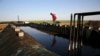 FILE - A former farmer at a primitive refinery makes crude oil into diesel and other products in Syria, April 6, 2018.