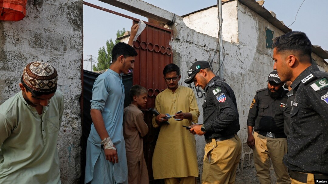 Pokiston politsiyasi afg'on qochoqlarining hujjatini tekshirmoqda, Karachi, Pokiston, 2023-yil, 21-noyabr.