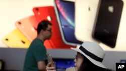 A customer looks at her iPhone in a store of U.S. tech company Apple in Beijing, May 10, 2019. 