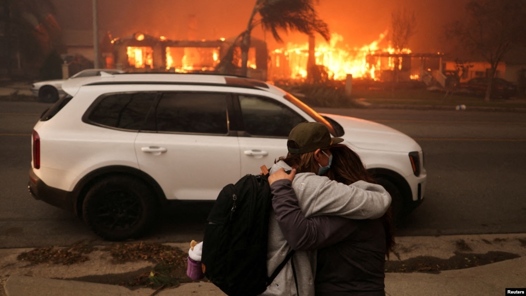 Personas se abrazan mientras evacúan luego de que los fuertes vientos alimentaron incendios forestales devastadores en el área de Los Ángeles. Foto captada en Eaton, Altadena, California, el 8 de enero de 2025.