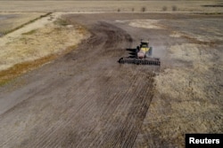 An agricultural worker operates farming equipment to plant wheat on farmland in Comodoro Py, outside of Buenos Aires, Argentina on June 21, 2022. (REUTERS/Matias Baglietto)